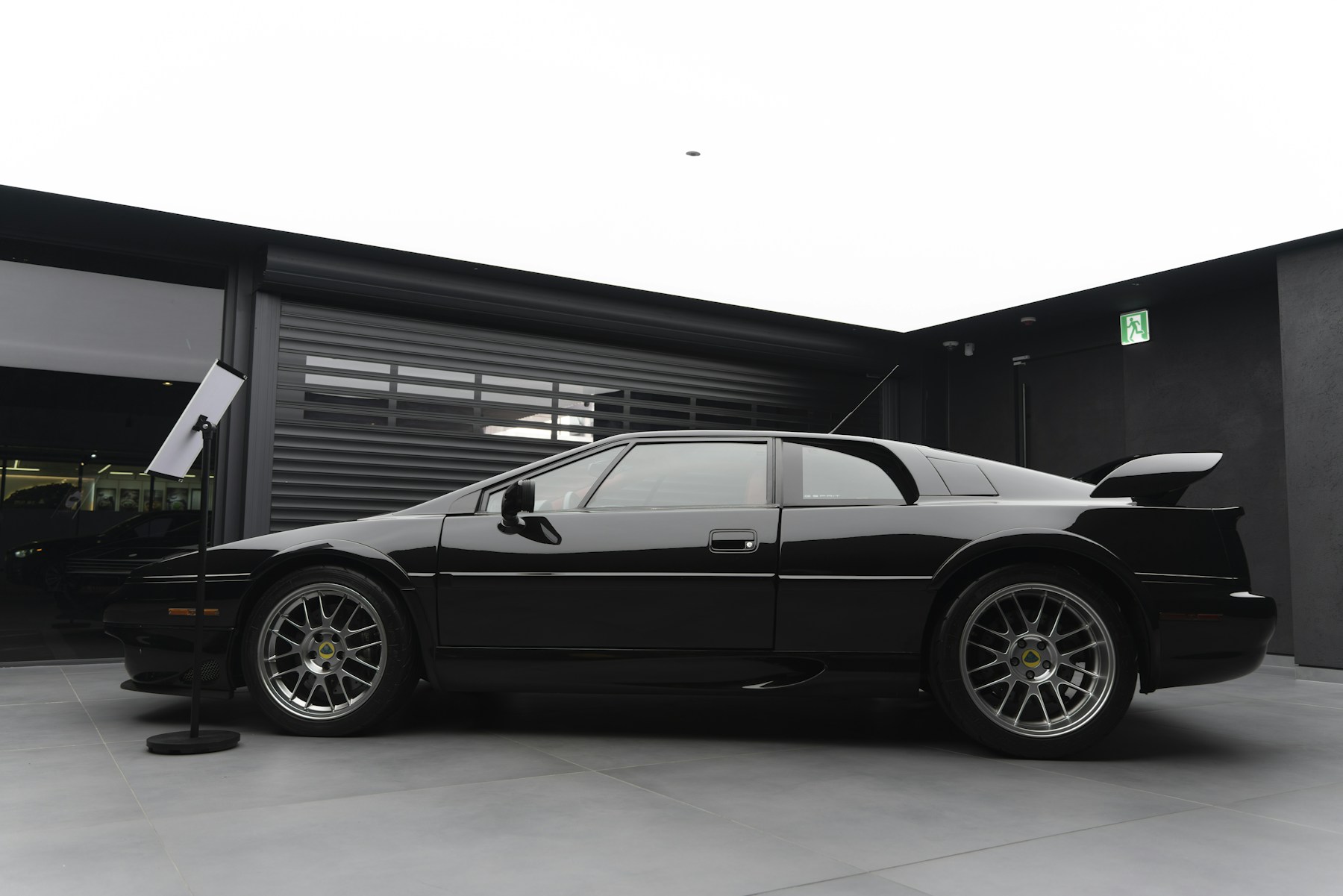 Black sports car outside a garage. Photo by Hoyoun Lee on Unsplash.